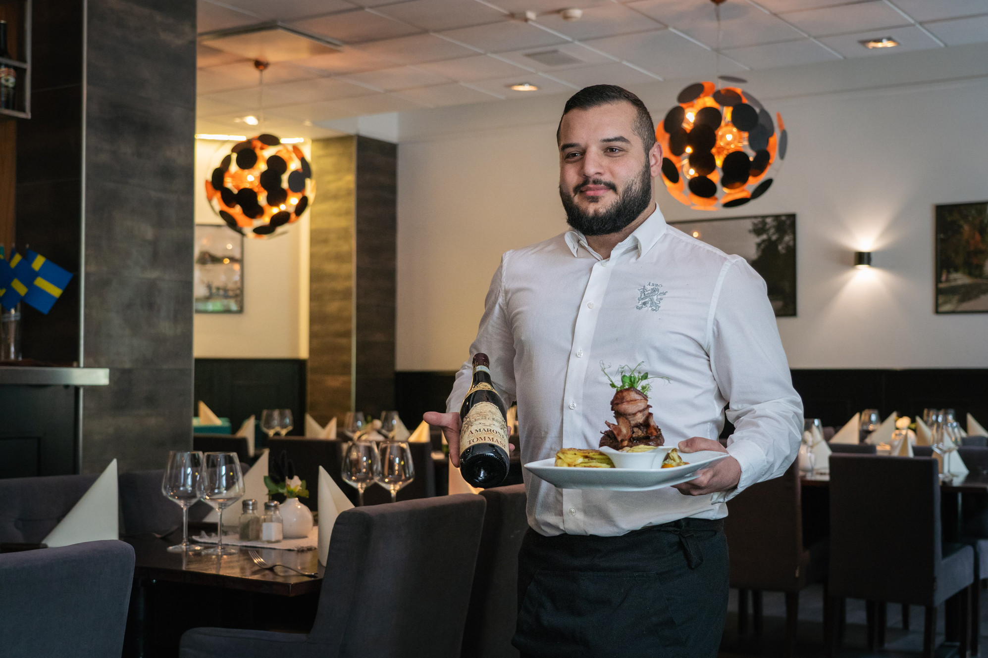 Servitör med vin och mat på en restaurang i Skövde